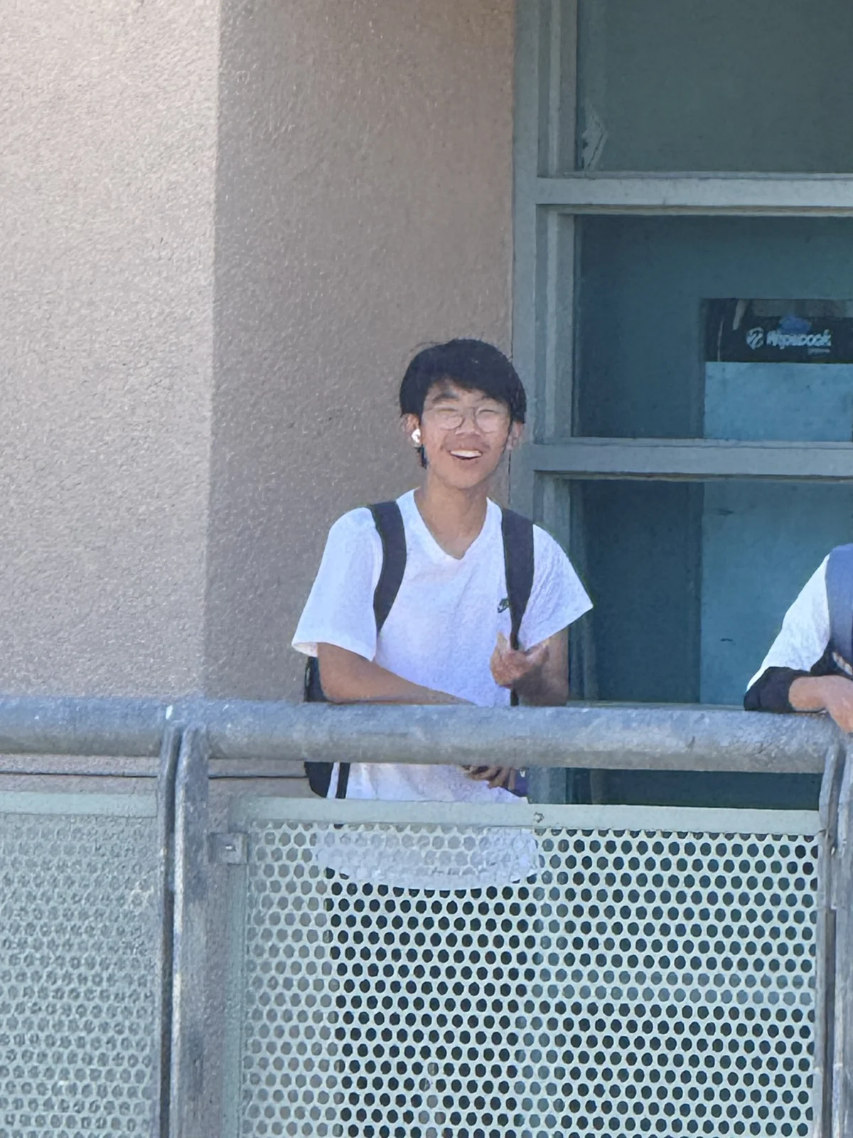 Smiling behind a railing outside