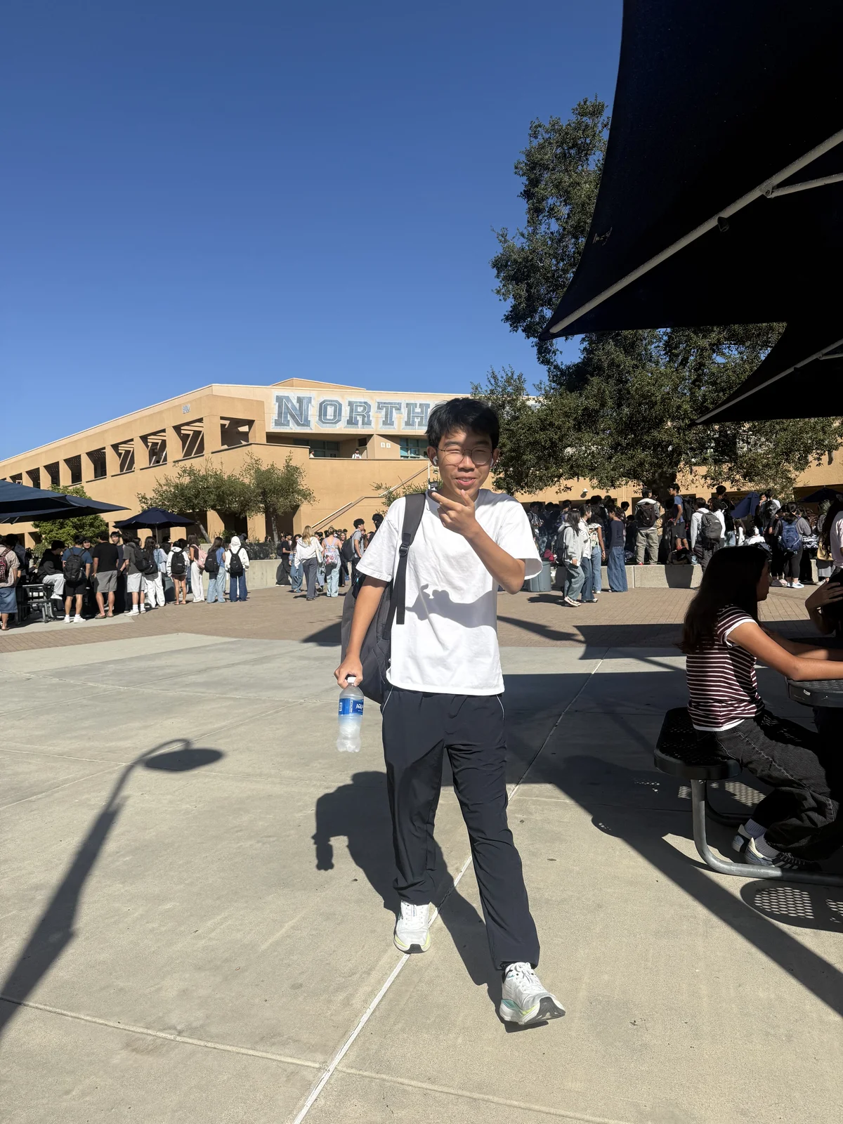 Posing in a sunny courtyard with a backpack and water bottle