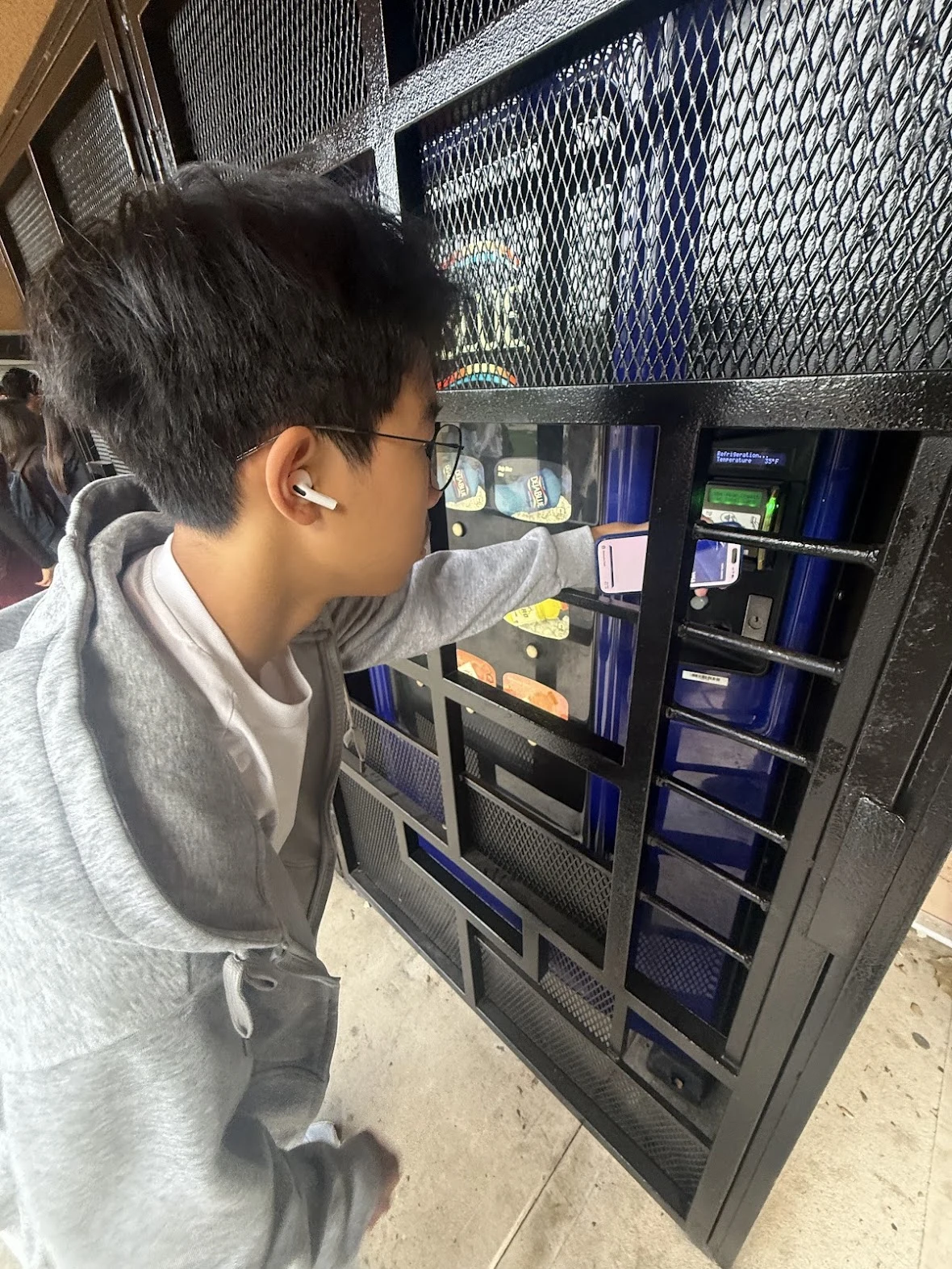 Using a phone at a vending machine behind a metal gate